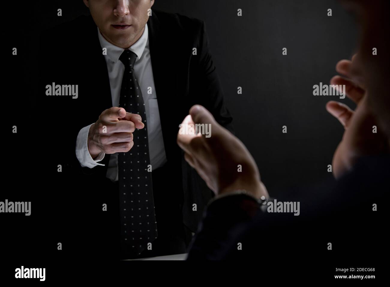 Detective pointing hand to suspect or criminal man in dark interrogation room Stock Photo