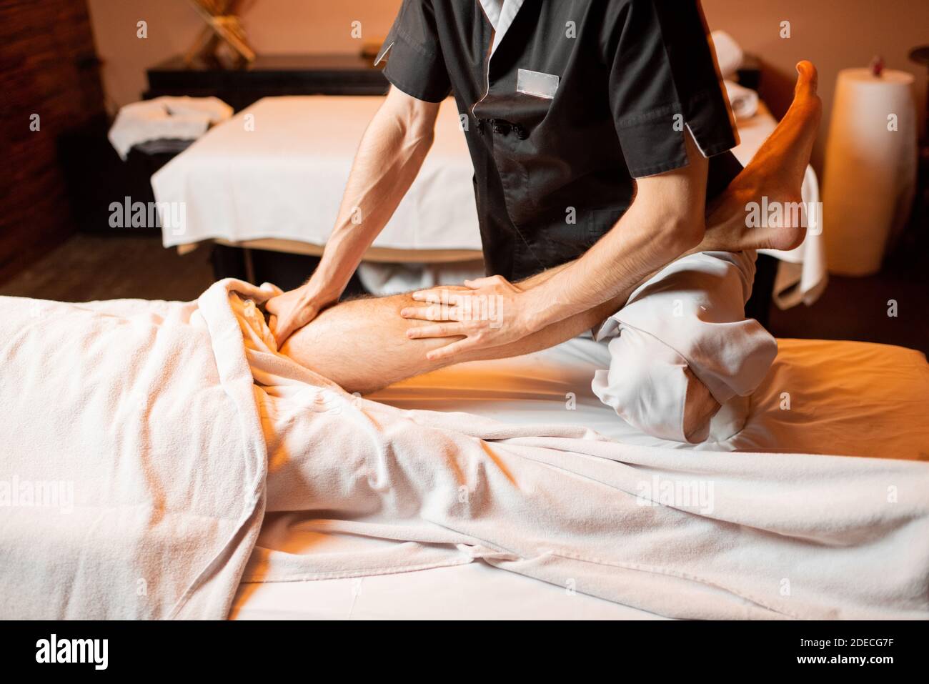 Professional therapist doing a deep massage to a male client at Spa salon.  working on the lower body Stock Photo - Alamy