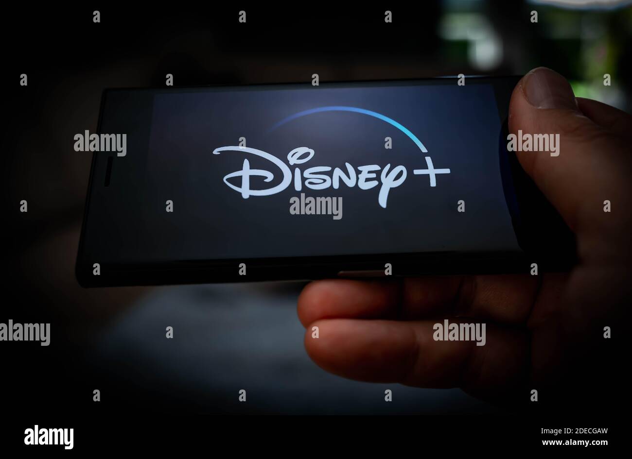Hand holding a mobile phone with a Disney plus logo displayed on the