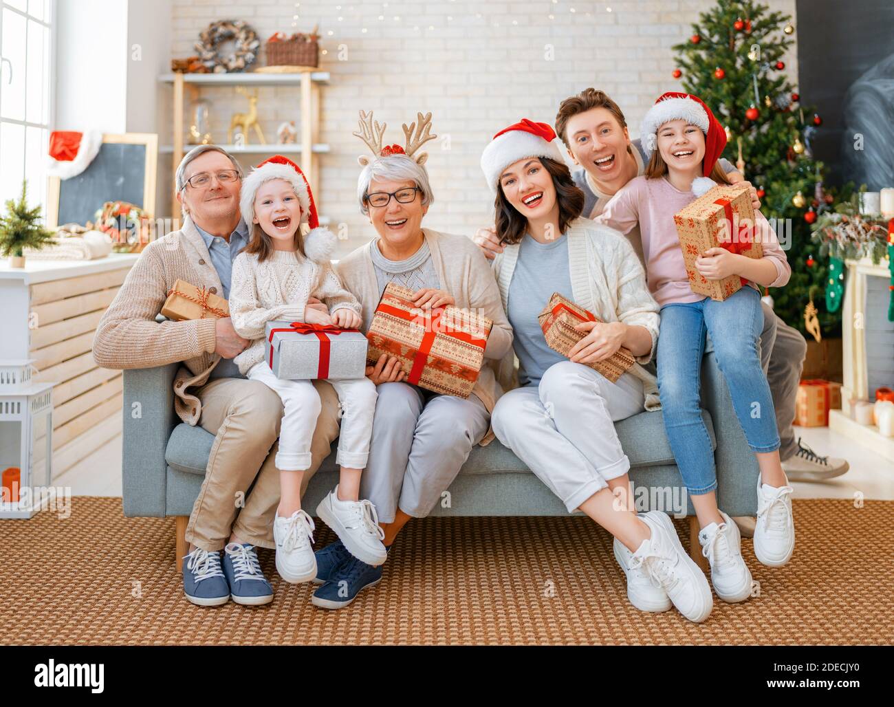 Premium Photo  Merry christmas and happy holidays! cheerful grandma and  her cute grand daughter girl exchanging gifts. granny and little child  having fun near tree indoors. loving family with presents in