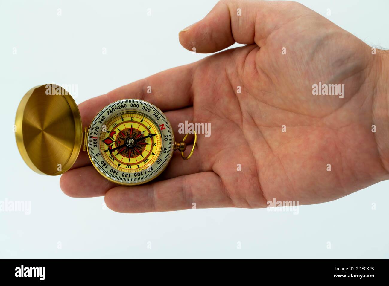 Antique golden pocket compass in the palm of a hand, isolated on white background. . High quality photo Stock Photo