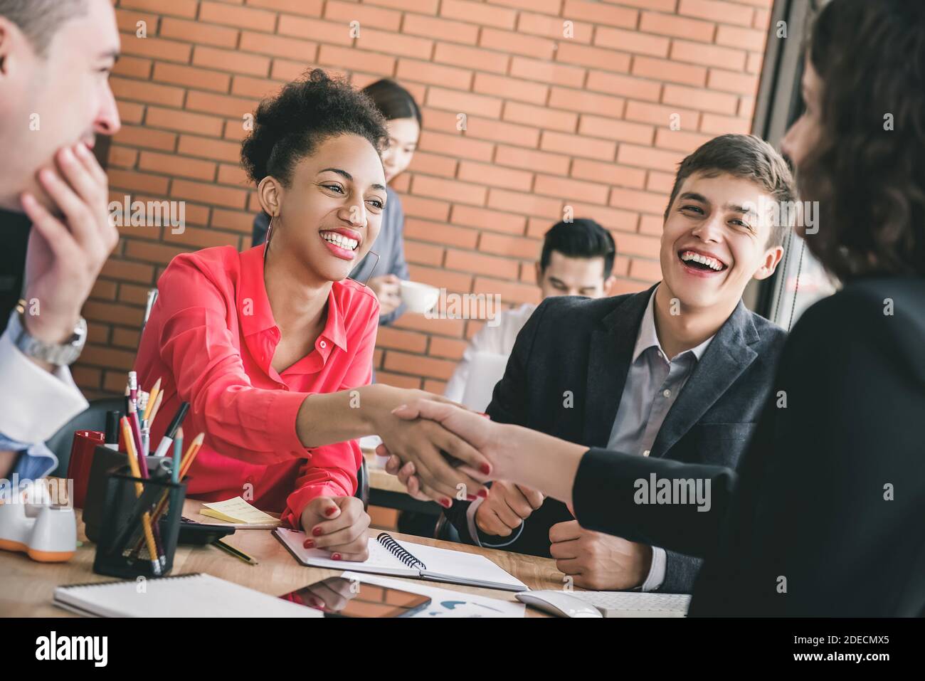 Smiling happy black businesswoman shaking hands with partner at office meeting offering congratulations on successful business deal Stock Photo