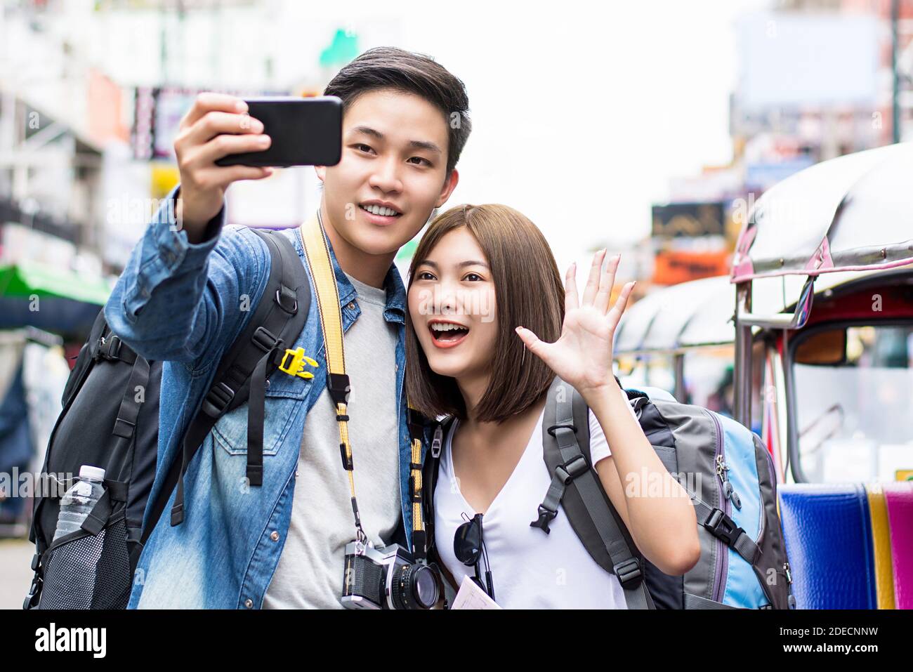 Asian couple tourist backpackers taking selfie with smartphone while traveling on holidays in Khao San road Bangkok Thailand Stock Photo