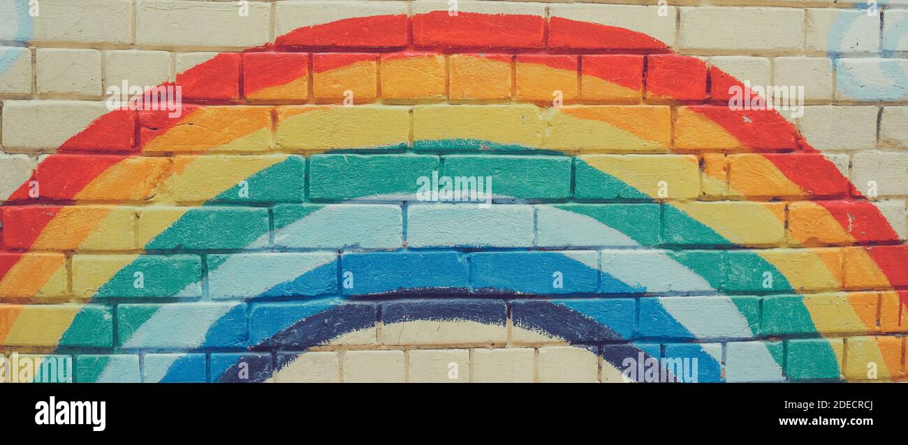 An image of the Rainbow flag painted on a brick wall in an urban ...