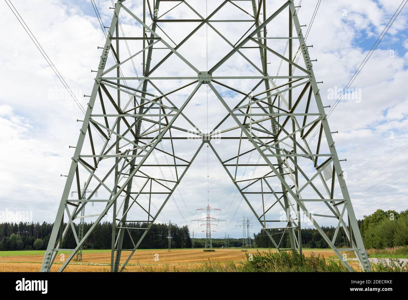 Oberbrunn, Germany - Aug 23, 2020: View through and along an overhead power line. Symbol for enery, energy transmission and power grid. Stock Photo