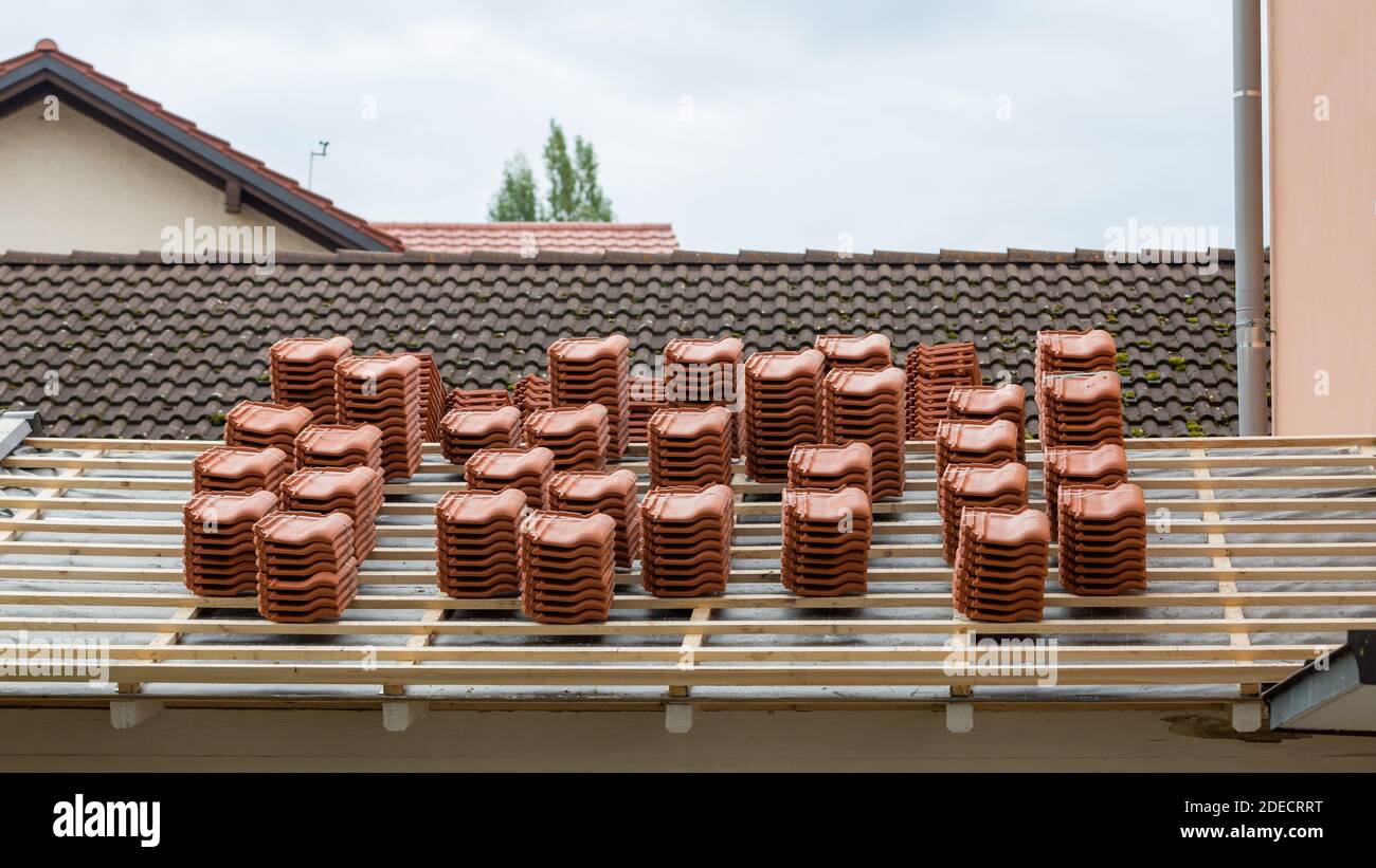 Stacks of roof tiles on a roof under construction. Symbol for roofer as a profession or the building construction Stock Photo