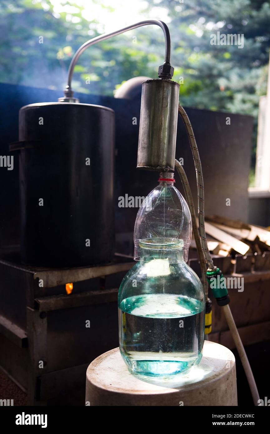 Moonshine flows from a homemade moonshine apparatus into a glass jar. Production of moonshine in Russia. Stock Photo