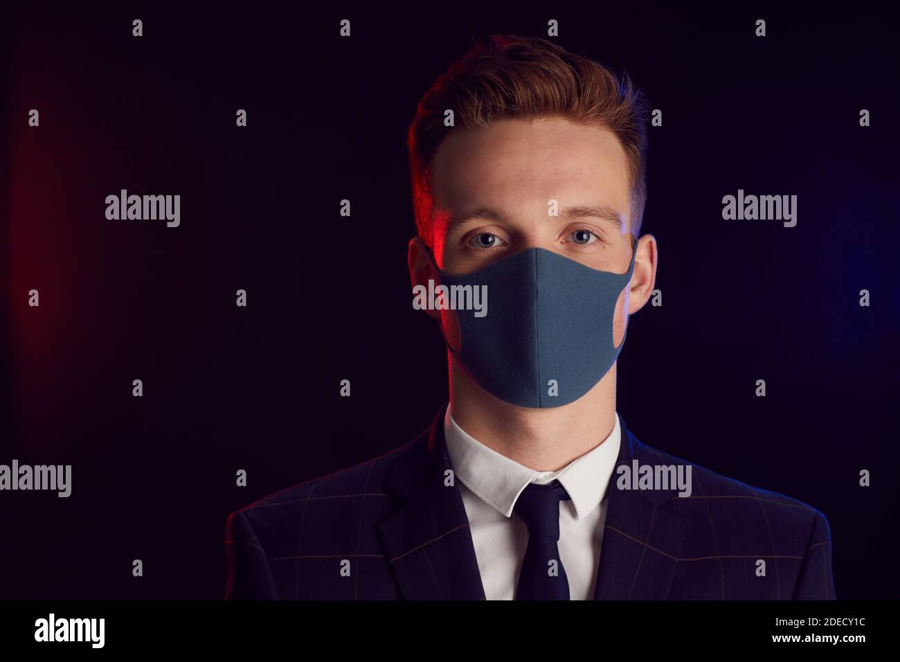 Portrait of young man wearing face mask and looking at camera while ...
