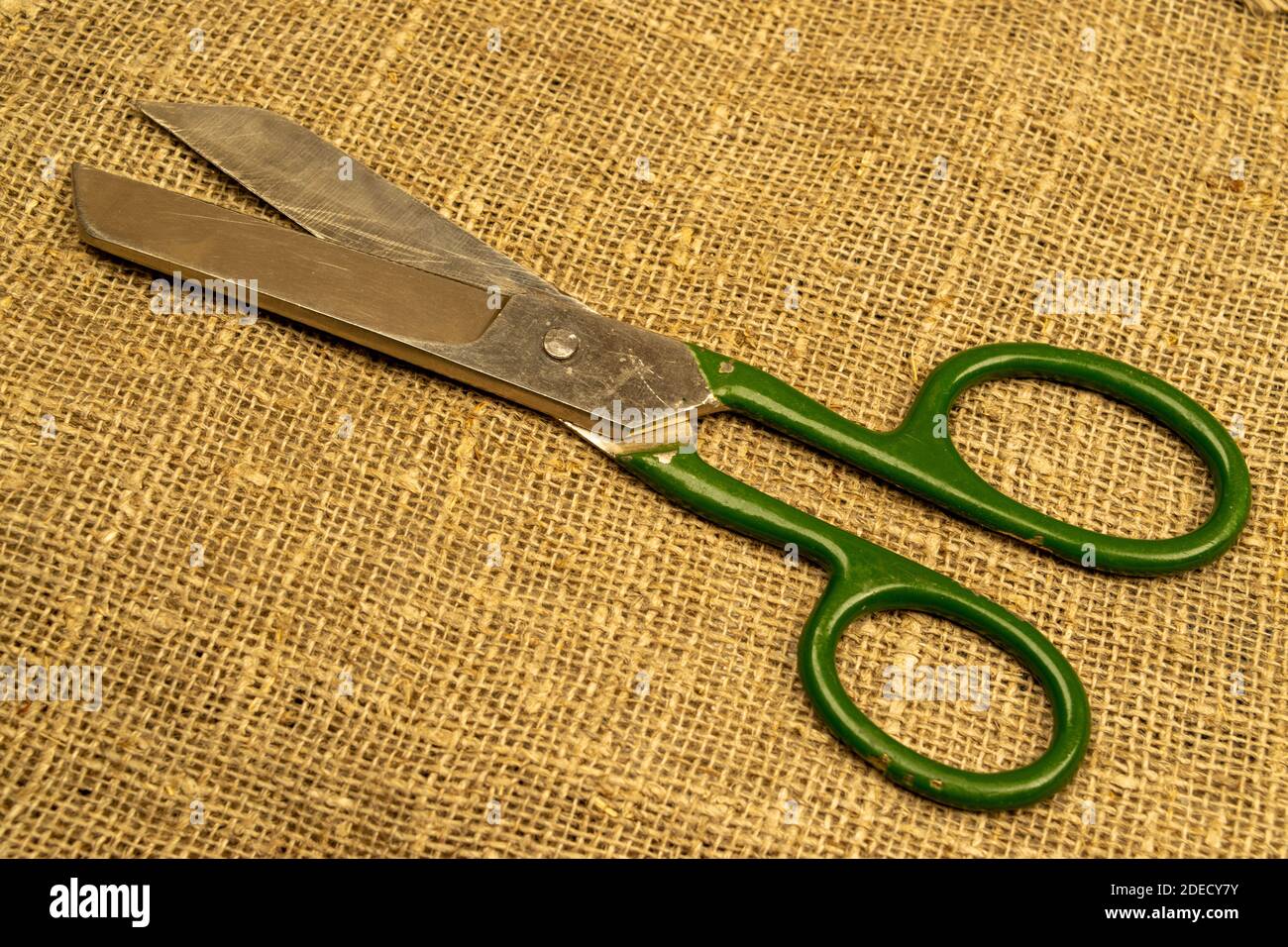 Large vintage scissors lie on rough homespun fabric. Close up Stock