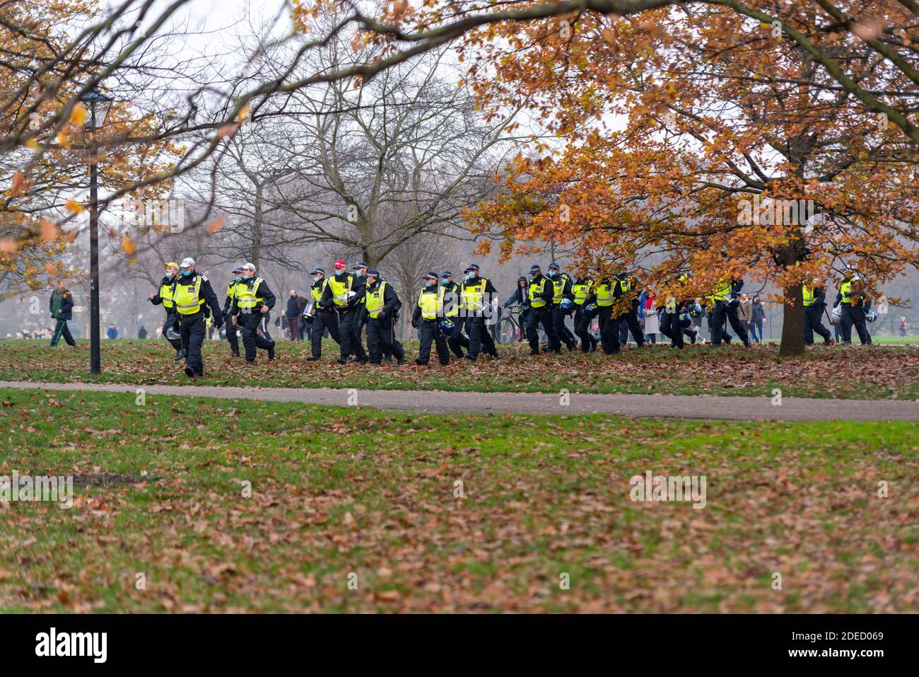 Police rushing to react to protesters at an anti lockdown protest in London, UK. A large group of police offers running through Hyde Park in Autumn Stock Photo