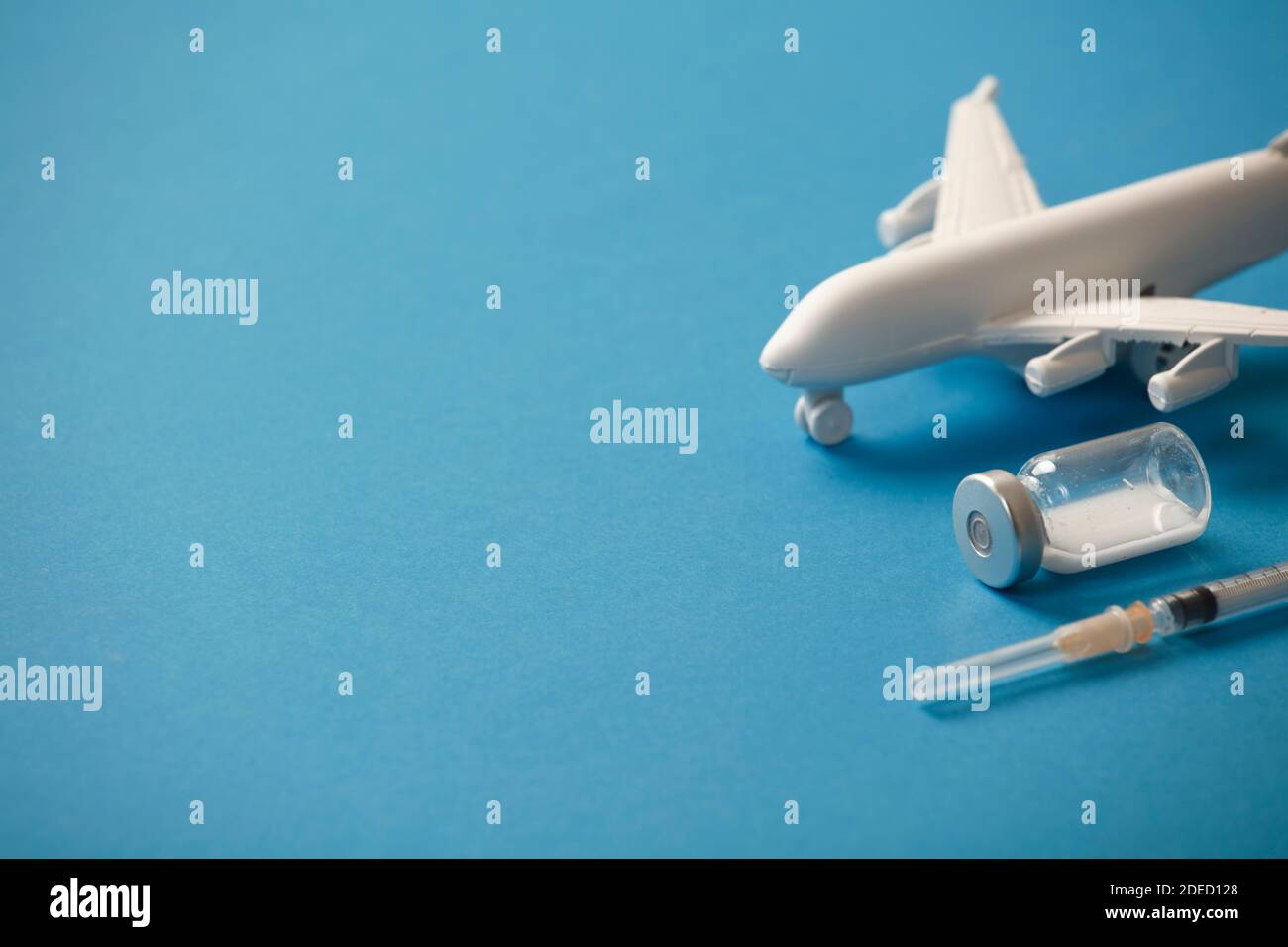 vaccine canister with syringe and white plane, blue background Stock