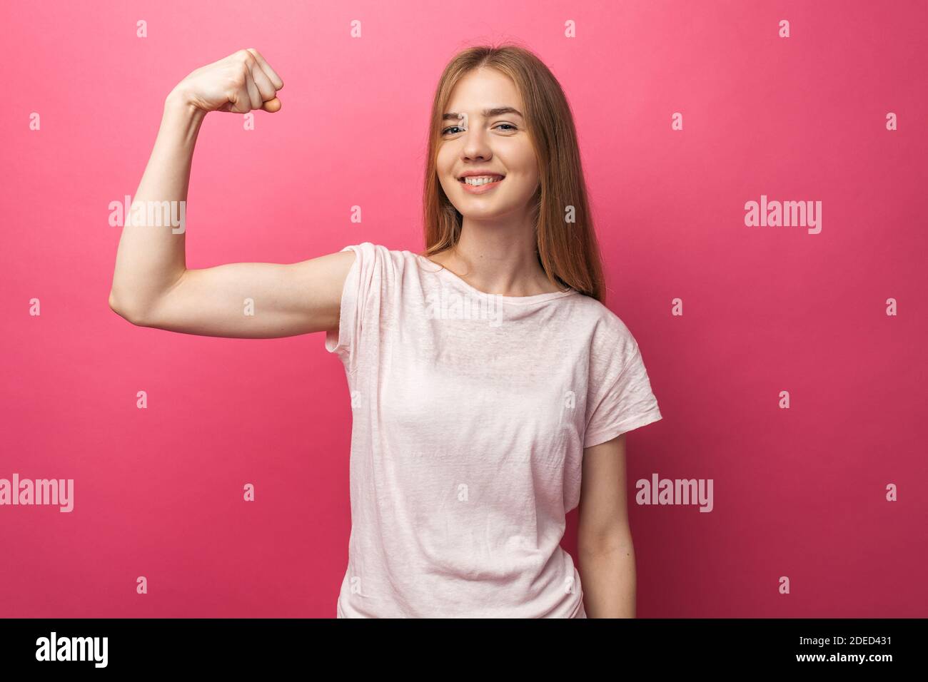 Portrait of cheerful young girl bending biceps isolated on pink background, Stock Photo