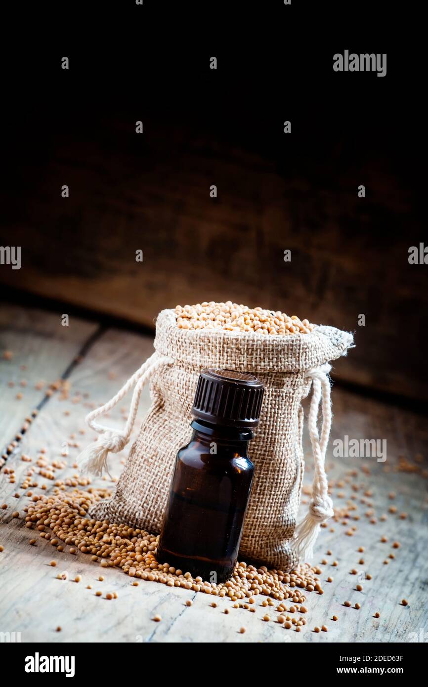 Essential oil of mustard in a small brown glass bottle, and mustard