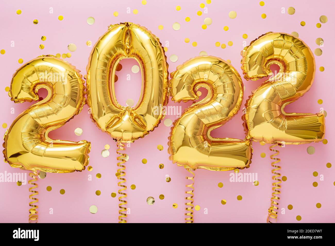 2022 year gold balloons on ribbons with confetti on pink wall. Happy New year 2022 eve celebration Stock Photo