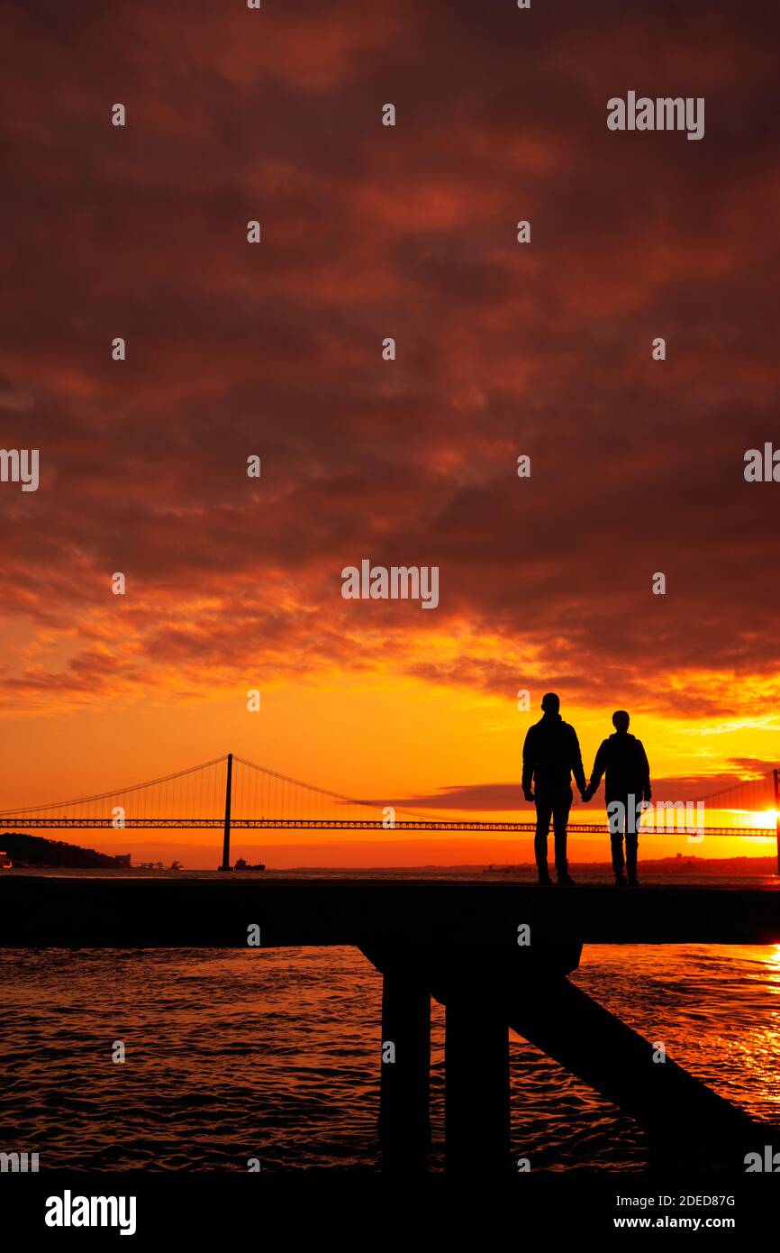 Silhouette of couple holding hands  a  bridge in the background sunset time, Lisbon Stock Photo