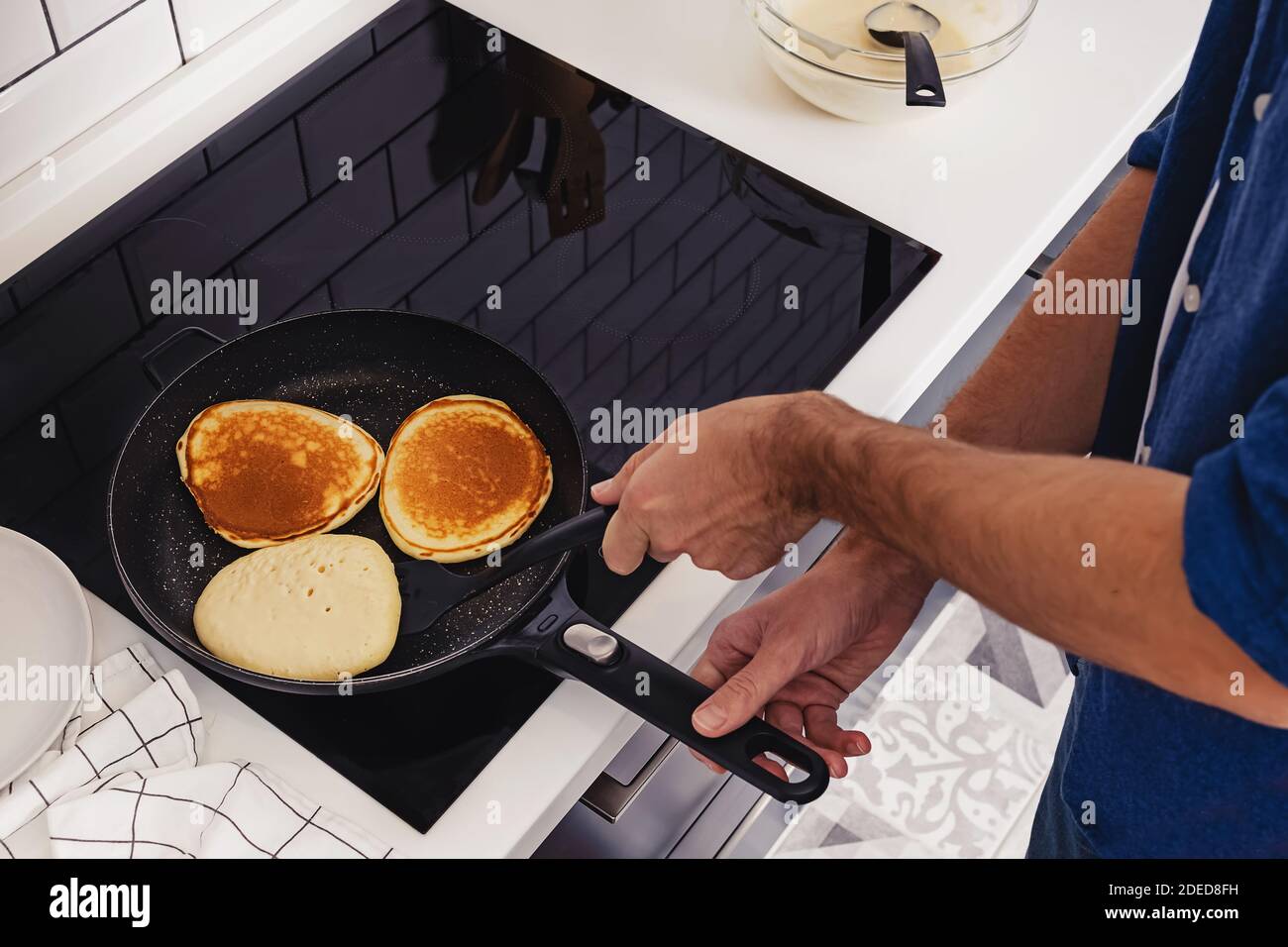 Man frying pancakes on the pan at his kitchen Stock Photo Alamy