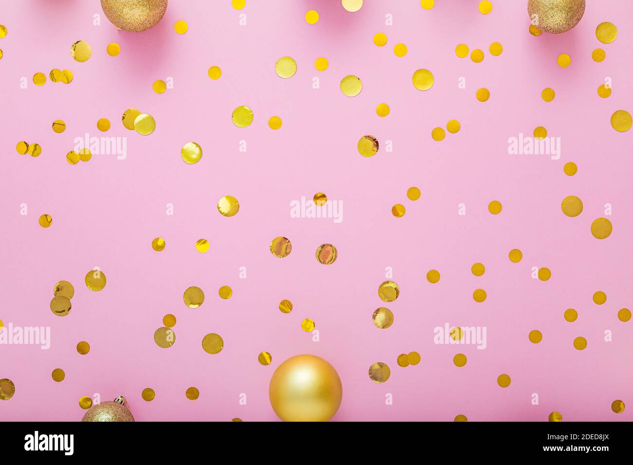Christmas gold festive decor balls, confetti on pink background. Flat lay copy space Stock Photo