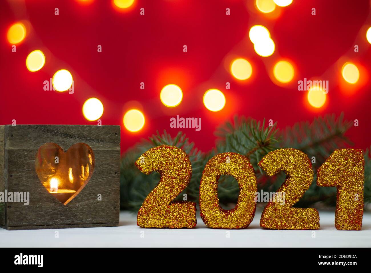 Glittering numbers 2021 with heart shaped candlestick and bokeh on red background. Merry christmas and a happy new year. Stock Photo