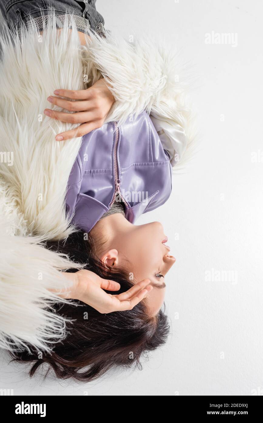 top view of elegant brunette young woman in stylish faux fur jacket ...