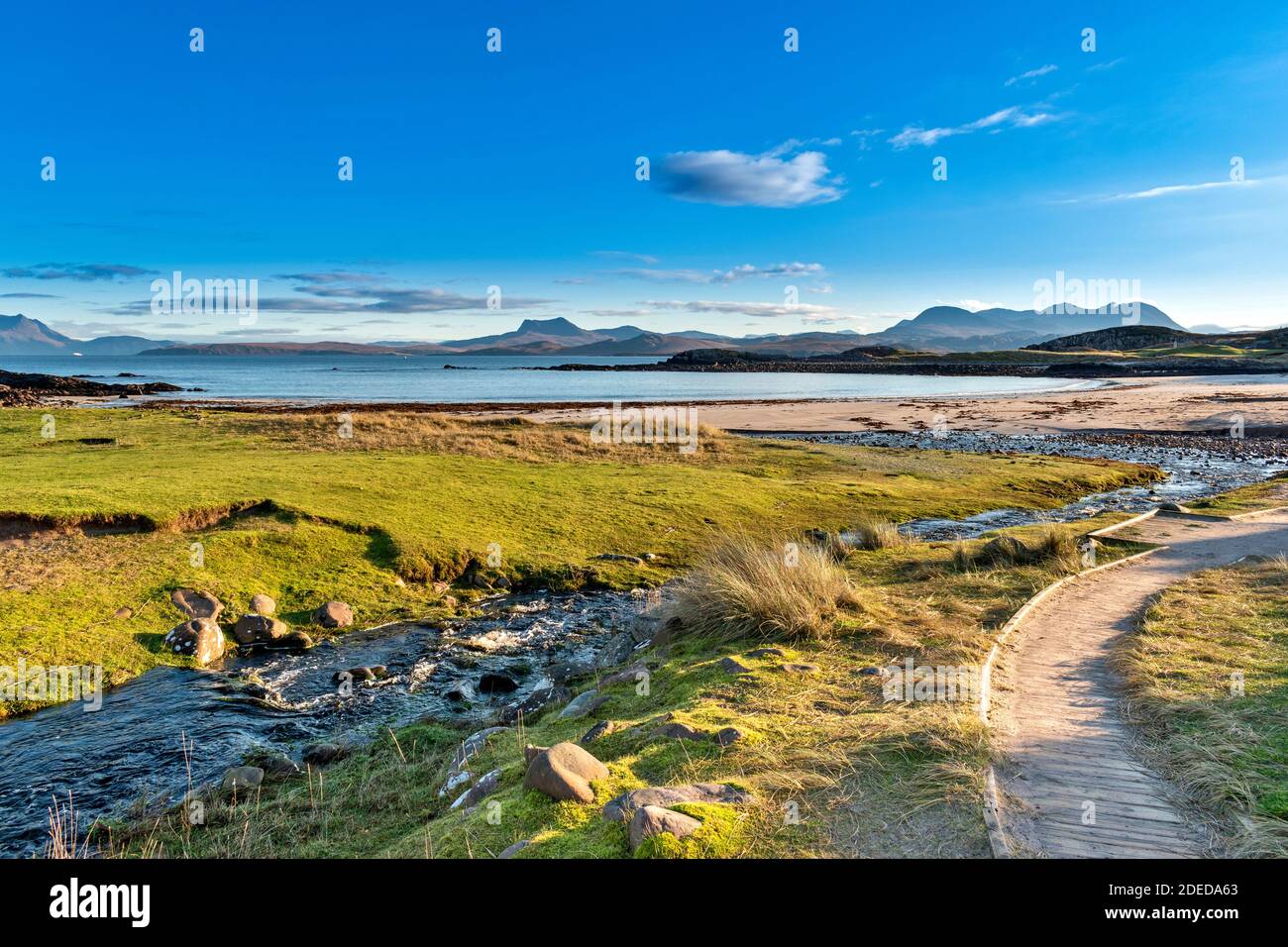 MELLON UDRIGLE ROSS-SHIRE HIGHLANDS SCOTLAND MORNING SUNSHINE BOARDWALK AND STREAM LEADING TO THE BEACH AND VIEW TO MOUNTAIN RANGES Stock Photo