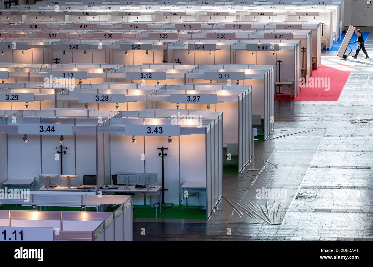 Munich, Germany. 30th Nov, 2020. A man drives through the still empty Contact Tracing Center with a hand truck on which a cupboard is loaded. The booths have been set up in Hall C2 of Messe Riem. Credit: Peter Kneffel/dpa/Alamy Live News Stock Photo