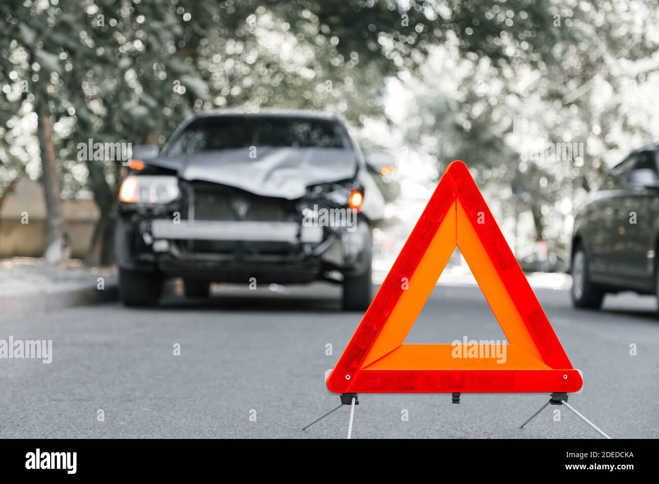 Red emergency stop triangle sign on road in car accident scene. Broken SUV car on road at traffic accident. Car crash traffic accident on city road Stock Photo