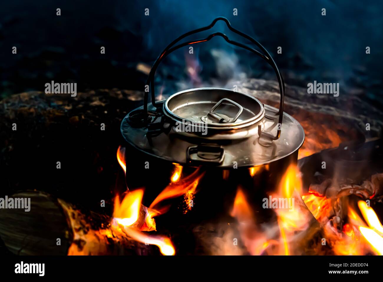 Steel kettle boiling water on the flames of a camp fire. Close up. . High quality photo Stock Photo