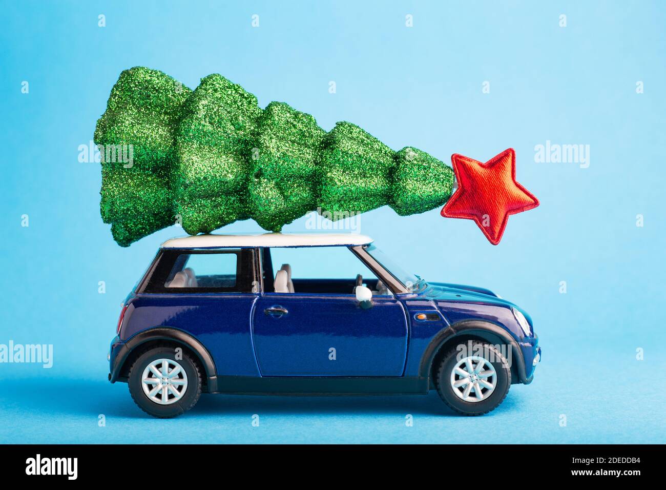 Christmas New Year tree with red star on top of blue car toy roof. Blue