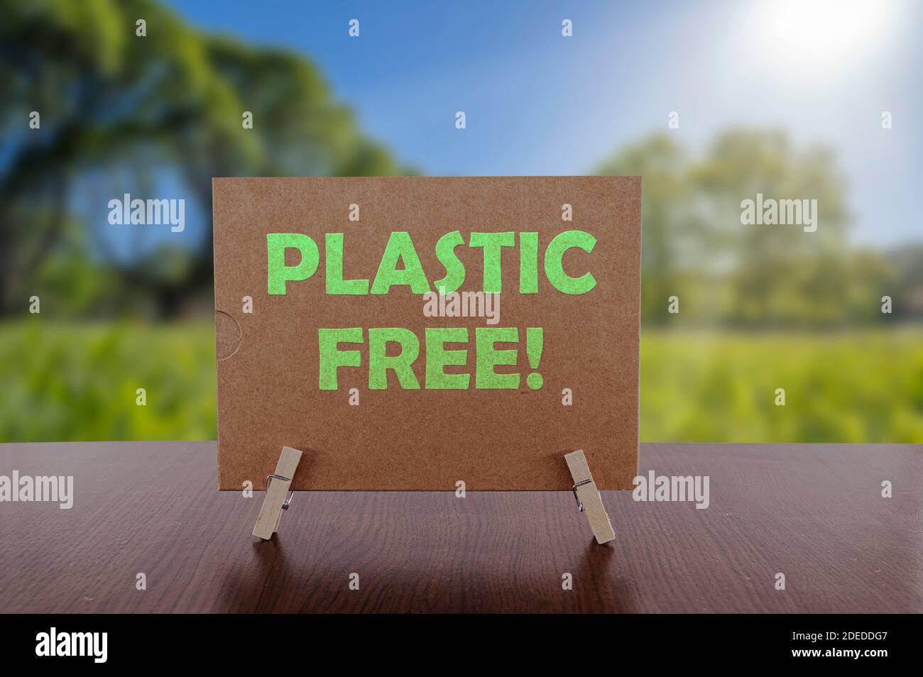 Plastic free text on card on the table with sunny green park background. Ecology concept, recycle, reuse, reduce waste. Stock Photo