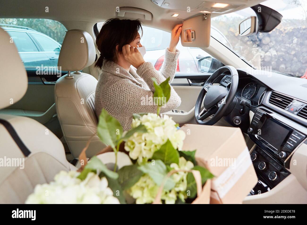 Car driver with face mask and packages in the interior makes a call as