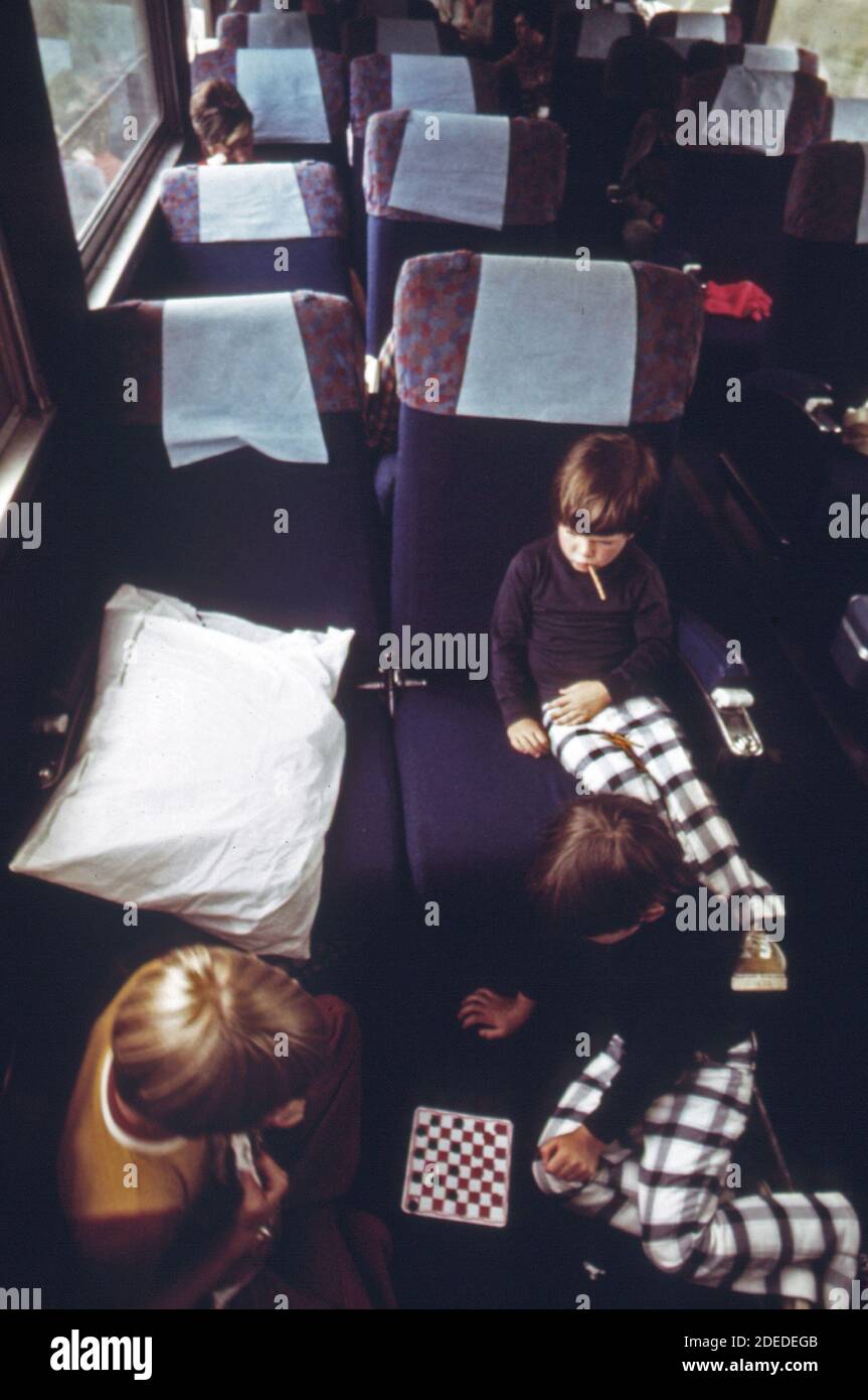 Youngsters play checkers between the seats of Amtrak's Broadway Limited on its way from Chicago to points east.  ca. 1974 Stock Photo