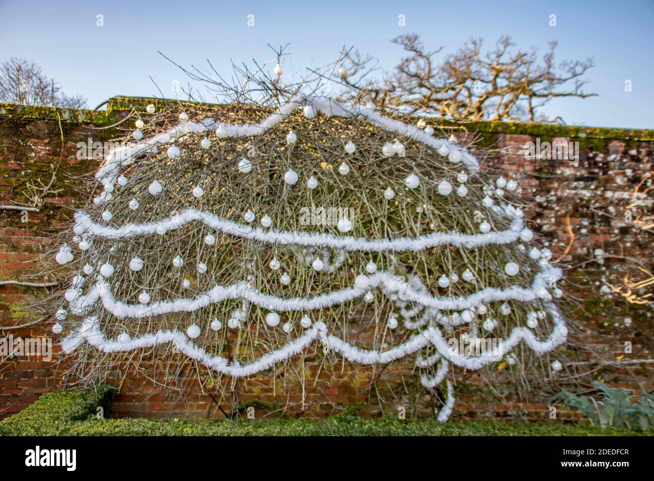 outside tree beautifully decorated with pretty white baubles and tinsel Stock Photo