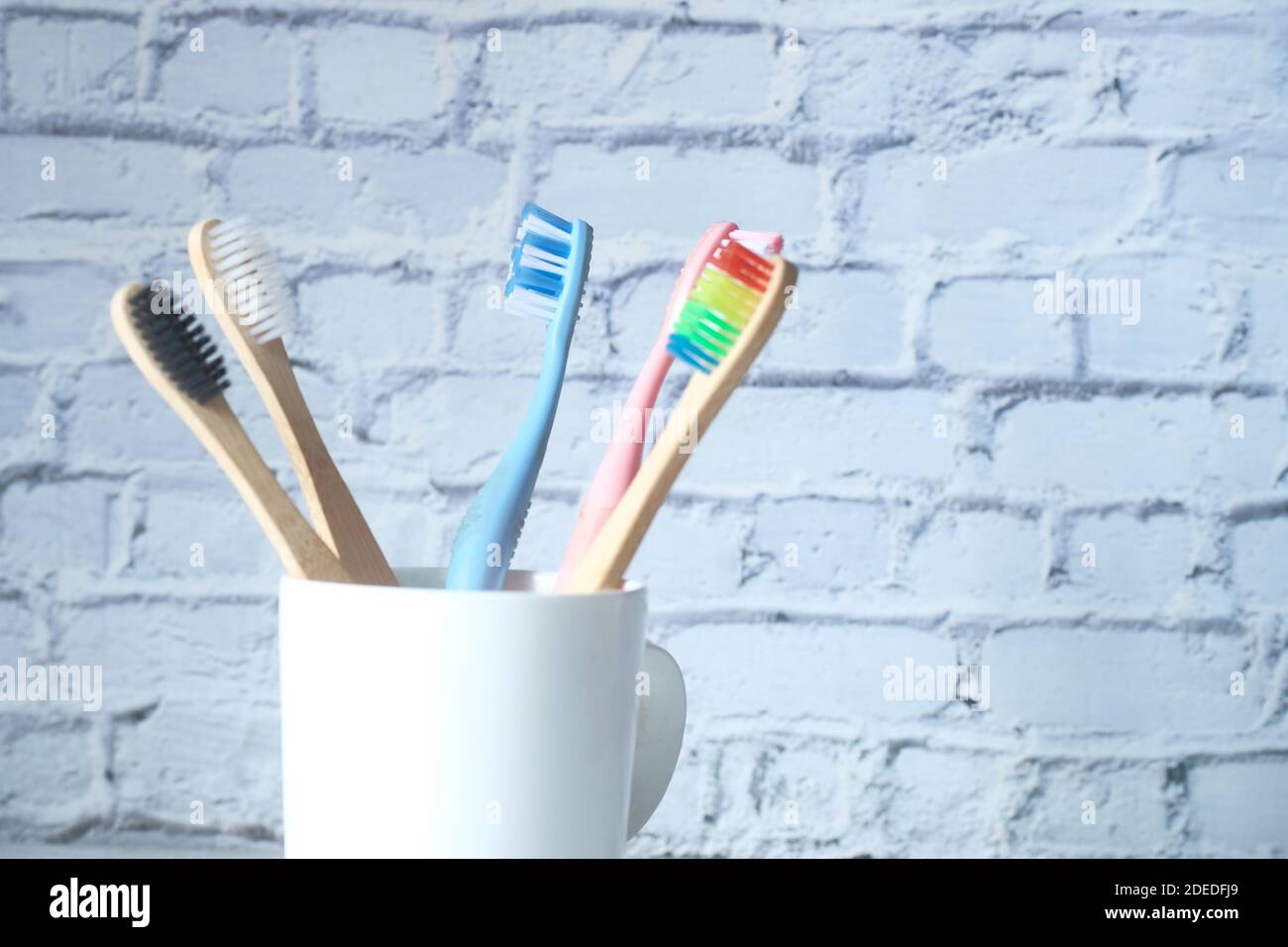 colorful toothbrushes in white mug against a wall Stock Photo - Alamy