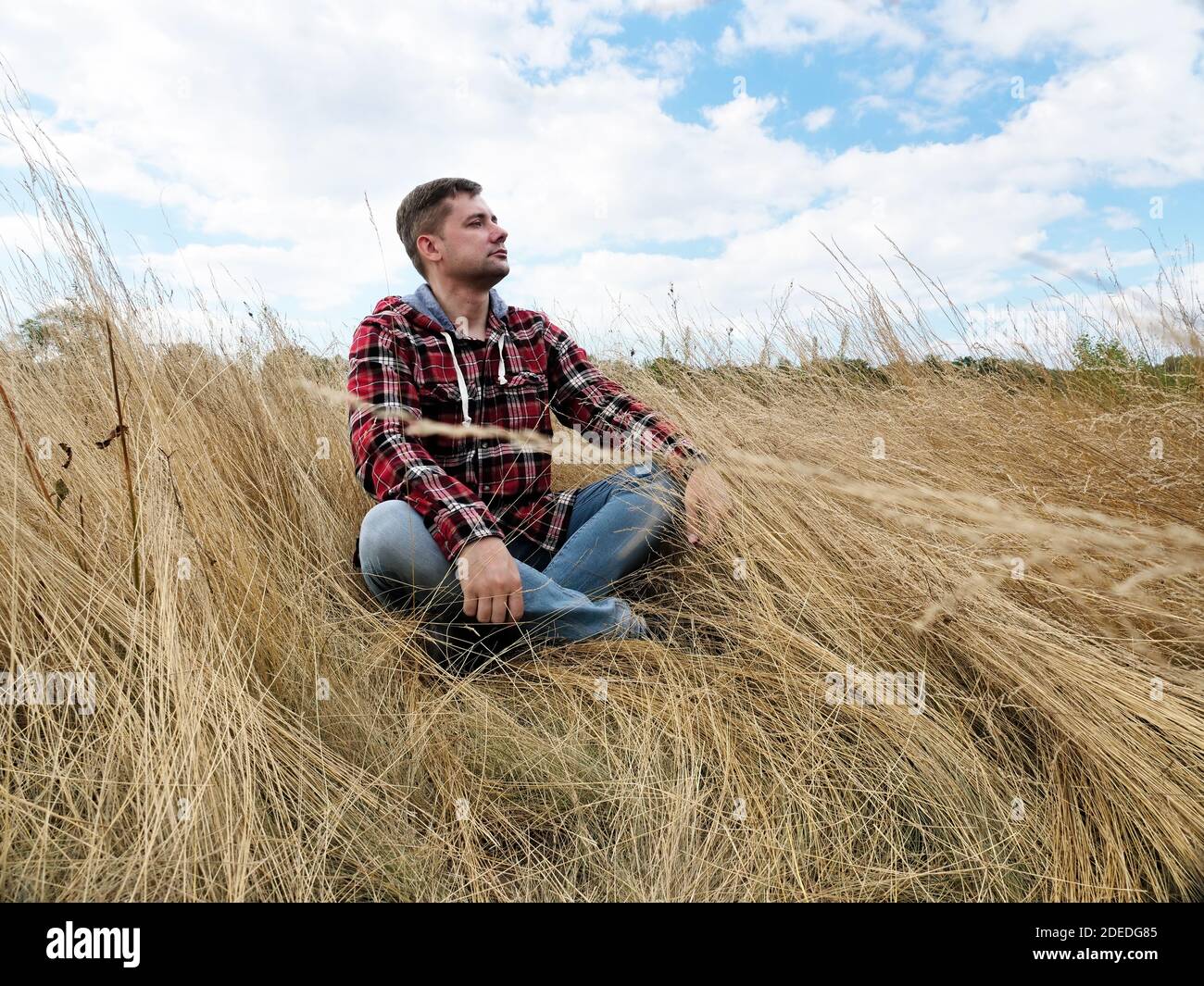 A man sits and relaxes in the middle of an autumn field in nature. Stock Photo