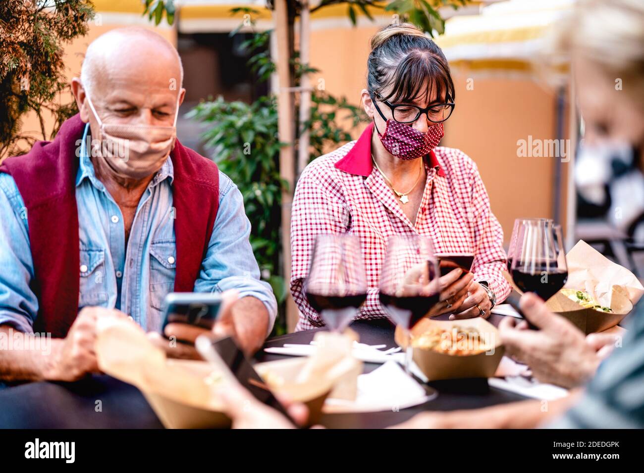 Senior people using mobile smart phone with face mask covered - Retired adults worried while watching news on smartphone - New normal lifestyle Stock Photo