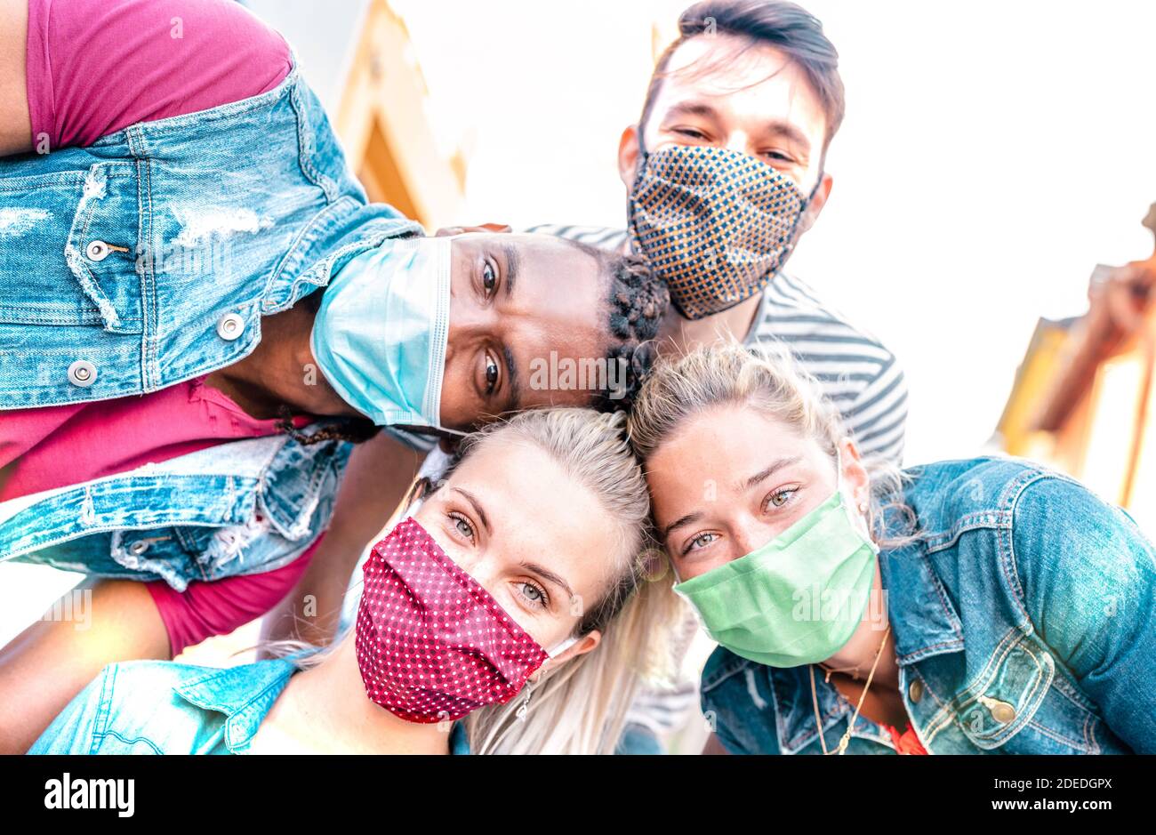 Multiracial millenial friends taking selfie smiling behind face masks - Happy friendship and new normal concept with young people having fun together Stock Photo