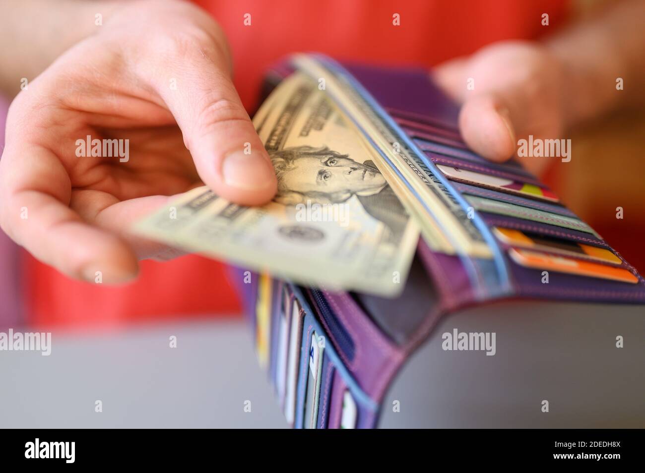 men's hands hold 20 dollar bills and a wallet on a gray table Stock Photo