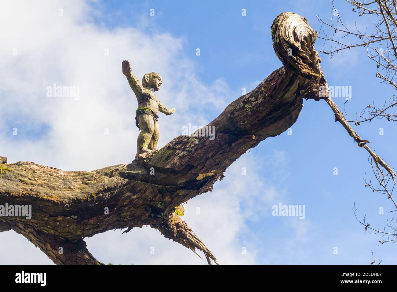 Carving of a child up a dead tree trunk in Baguio City, Philippines Stock Photo
