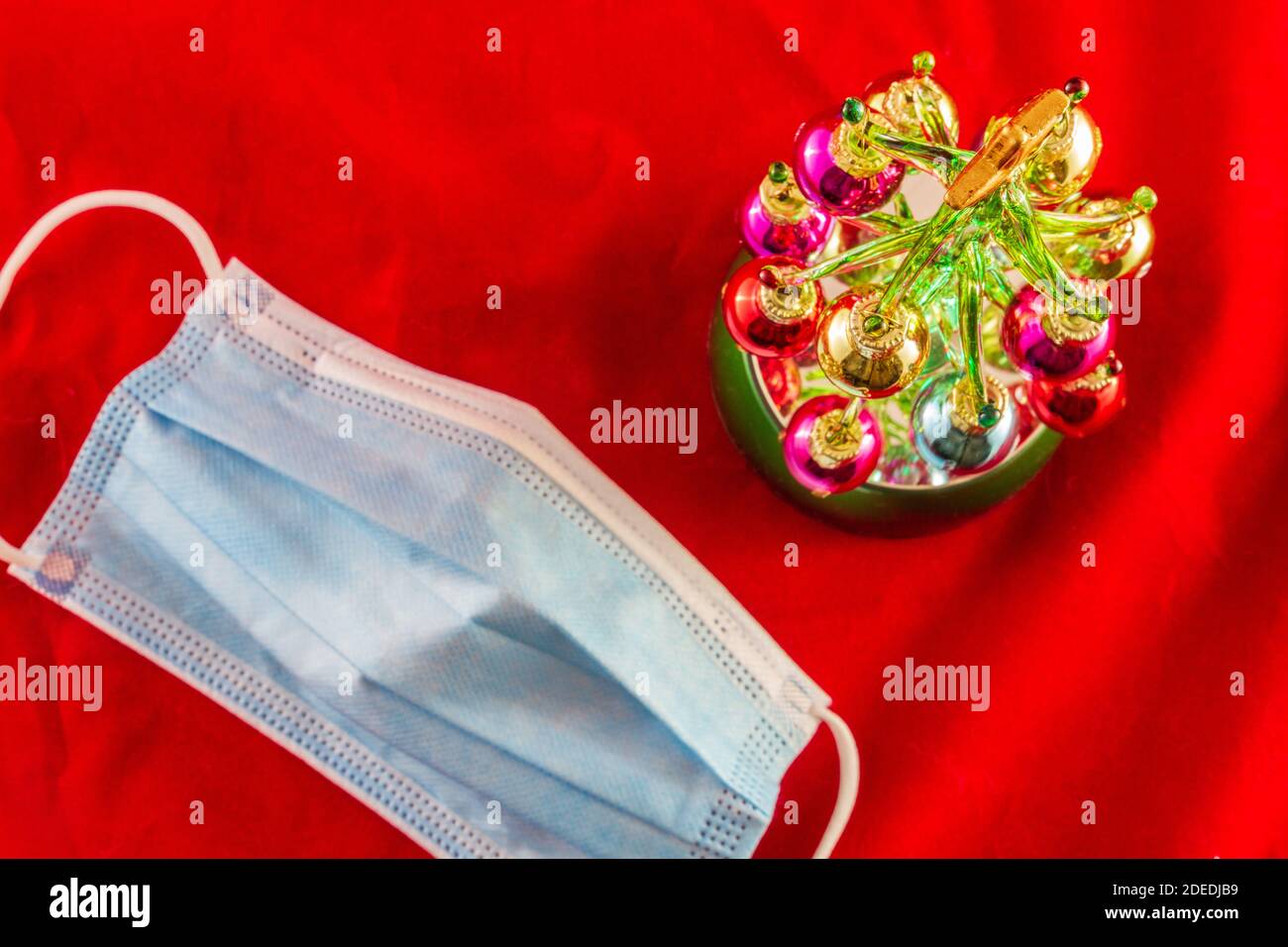 Mini Christmas tree next to a blue facemask, top view. Christmas in the covod-19 era concept photo. Stock Photo