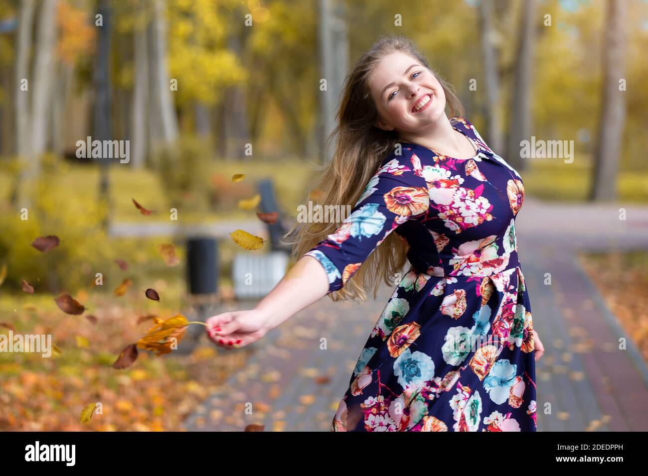 Happy blonde girl in the autumn park scatters leaves and laughs Stock ...