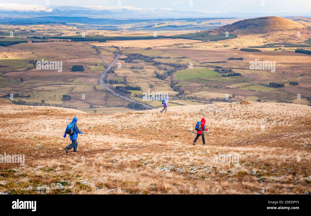 Fell walkers descending Blencathra a mountain also known as Saddleback in the English Lake District. Great Mell Fell is the distant   rounded hill Stock Photo