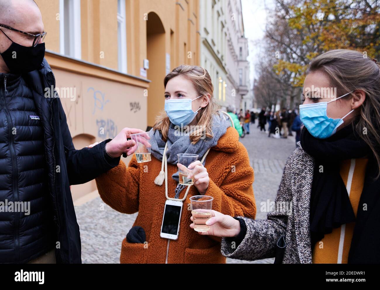Berlin, Germany. 28th Nov, 2020. Three friends from two households stand in a so-called 'drinking zone' and drink champagne. To contain the corona pandemic, these zones are marked at a weekly market in Prenzlauer Berg with a distance of about 2 meters. Credit: Annette Riedl/dpa-Zentralbild/ZB/dpa/Alamy Live News Stock Photo