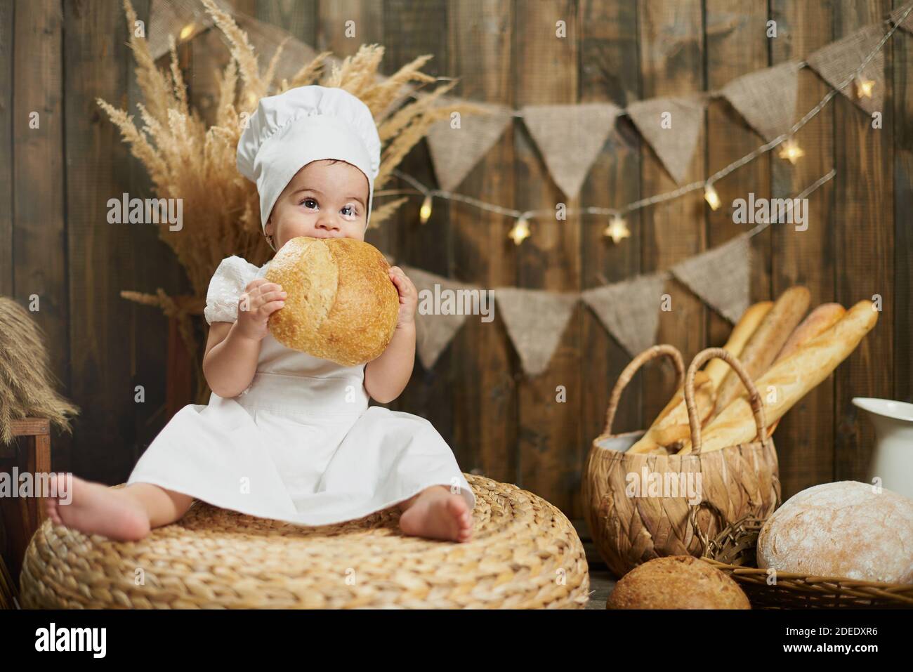 Little cute girl baker eating fresh bread Stock Photo