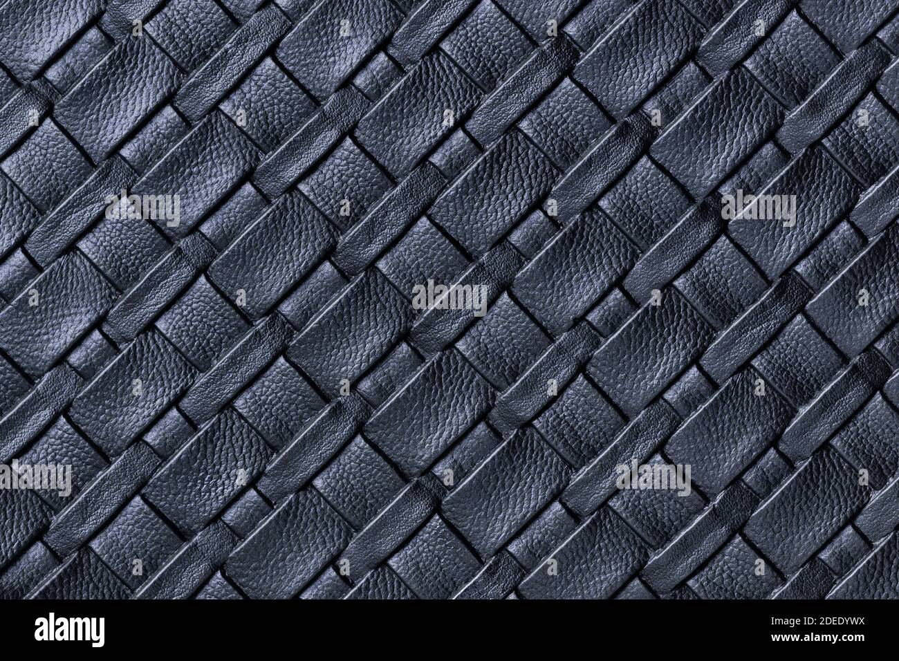 Texture of dark blue leather background with wicker pattern, macro. Abstract backdrop from modern decorative black textile with diagonal lines. Stock Photo