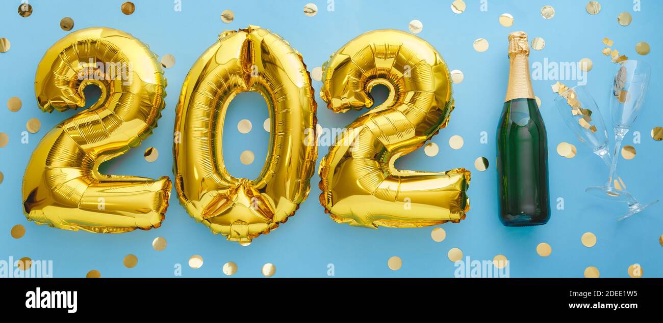 2021 golden air balloon numbers on blue background bottle of champagne and glasses with confetti. Happy New year eve invitation card with Christmas go Stock Photo