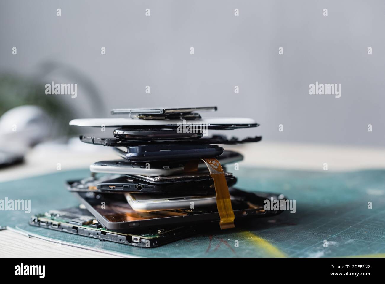 Close up view of pile with disassembled mobile phones and batteries with blurred workplace on background Stock Photo