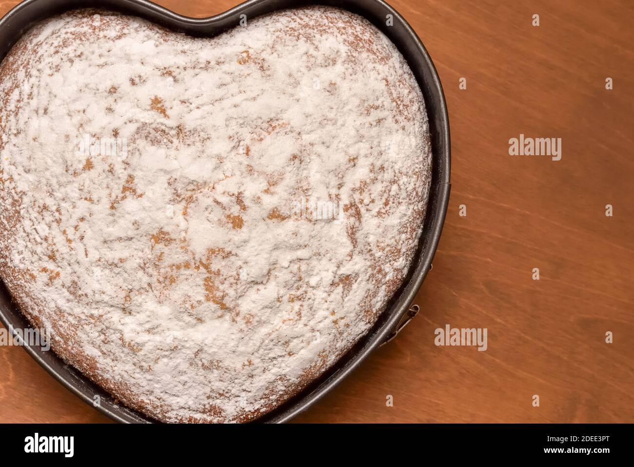 heart shaped cake in springform pan, freshly baked and dusted with