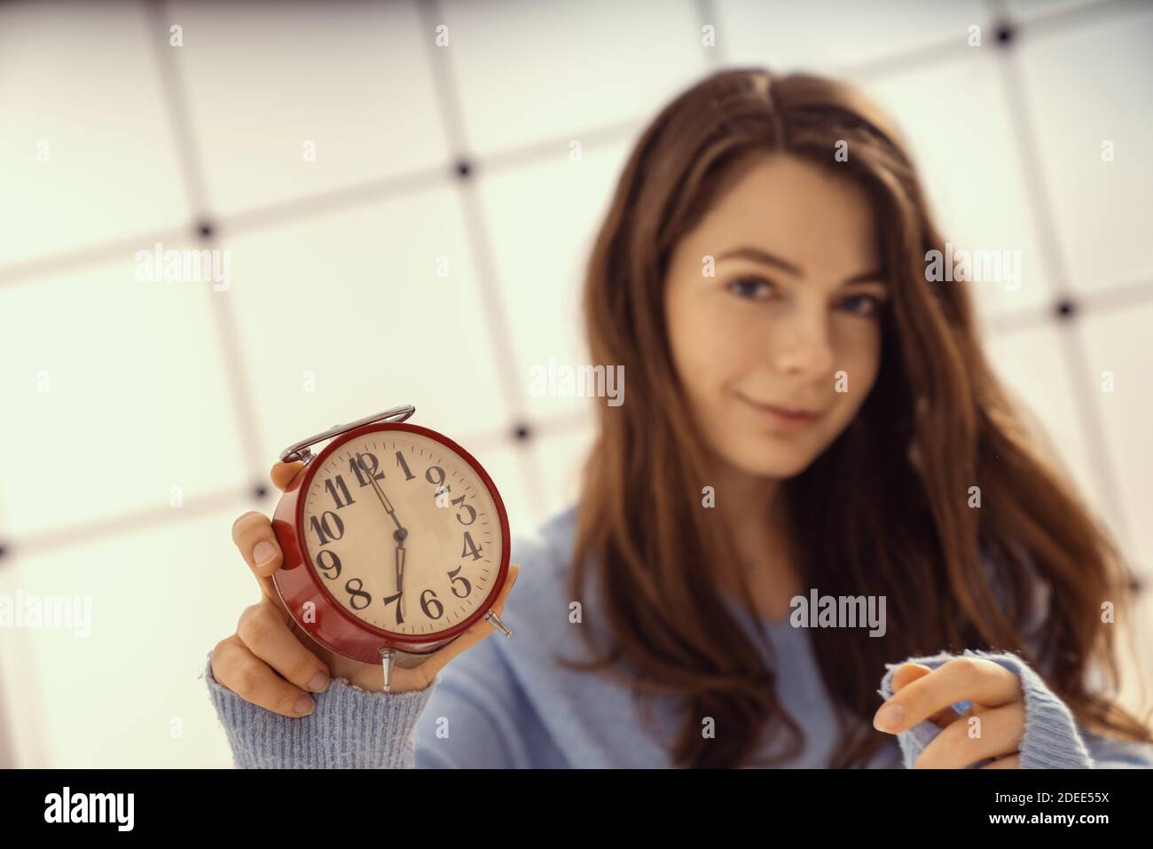 Beautiful young woman showing time on alarm clock Stock Photo Alamy