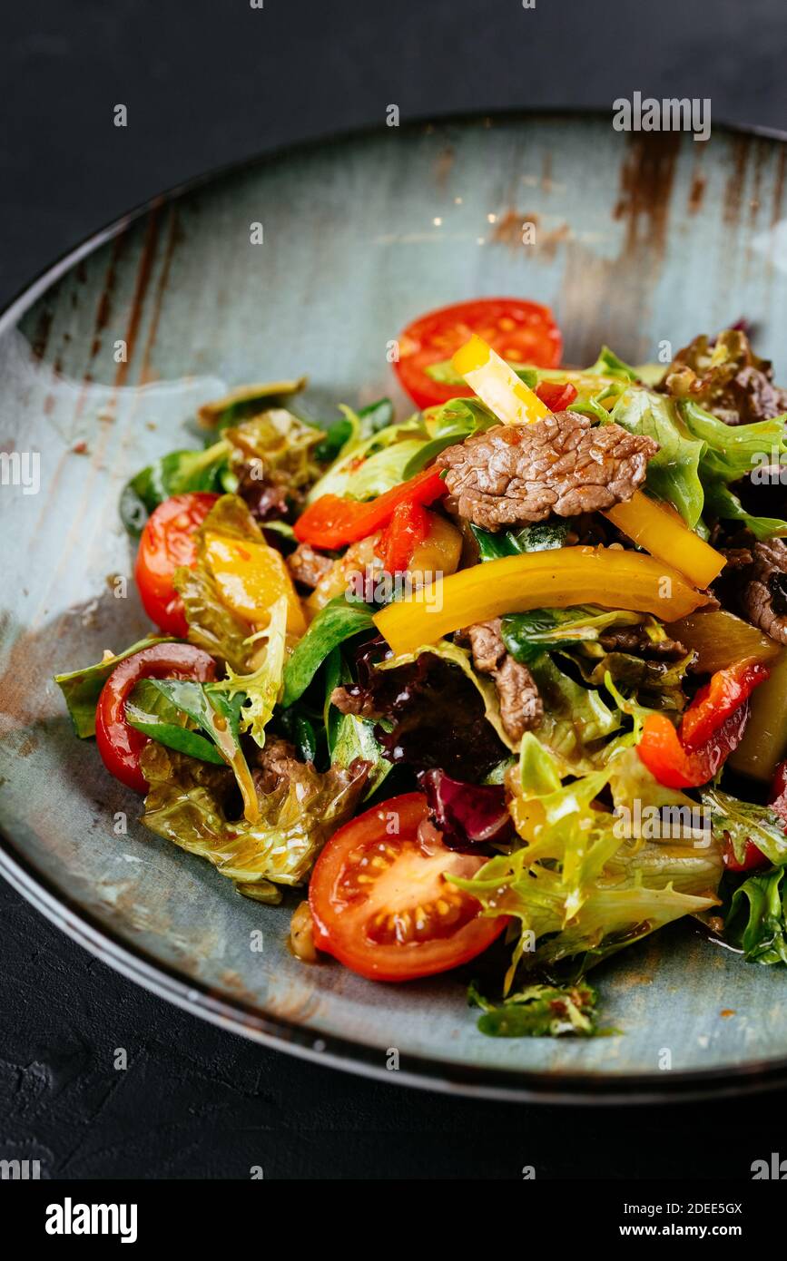 warm salad with marbled beef steak on a black background Stock Photo