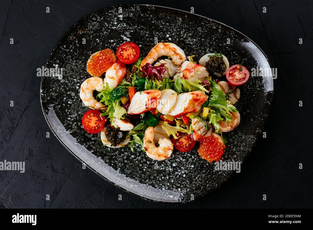 salad with shrimp, vegetables and crab meat on a black background Stock Photo